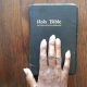an african american womans right hand with manicured nails rests on the holy bible